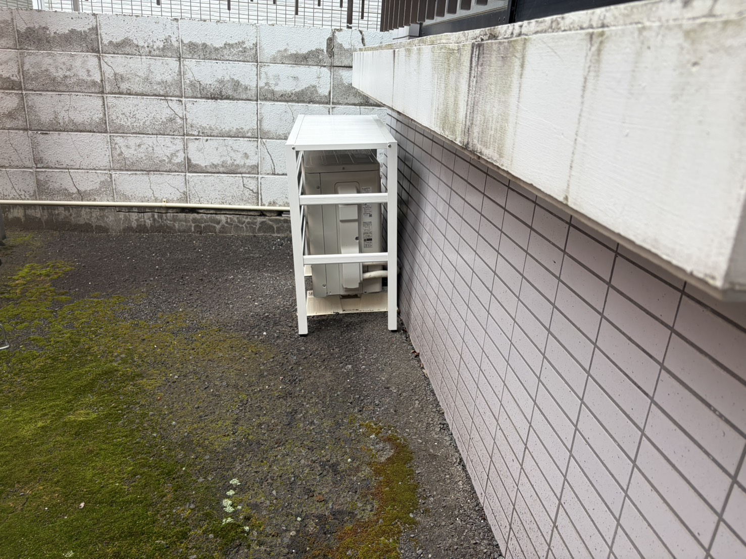 建物と塀のあいだの狭いスペースに設置した室外機カバーの側面